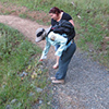 Two hikers pointing at plants next to trail